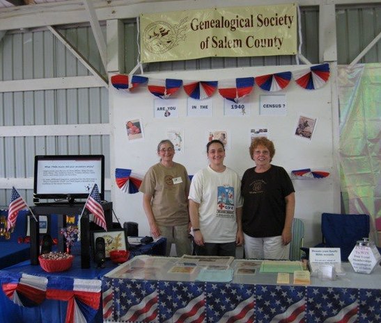 Three members pose at the Genealogical Society's 1940s Census themed booth