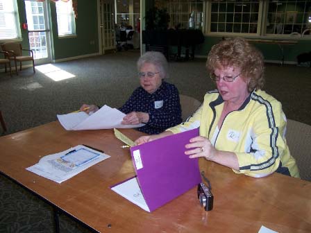 Emma Scholes from the Genealogical Society assists a participant with her papers.